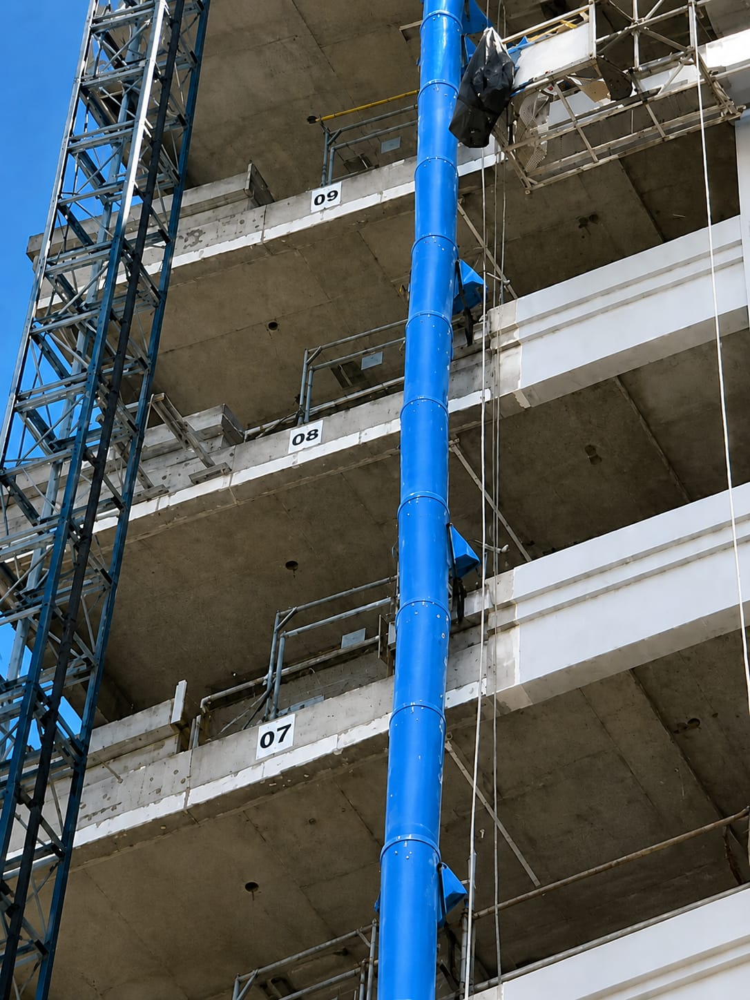 Condutor de entulho azul instalado em prédio em obra